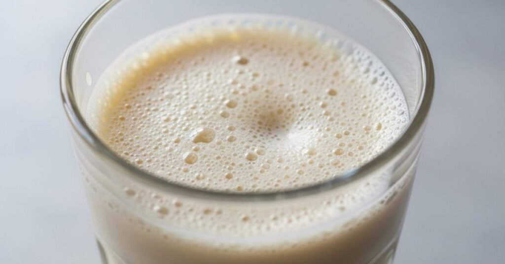 A close-up of collapsed almond milk foam in a glass By bestmilkfrother. com 